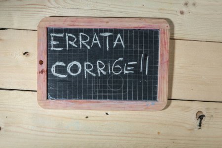 Foto de Pizarra negra sobre fondo de madera con la inscripción: "errata corrige" - Imagen libre de derechos