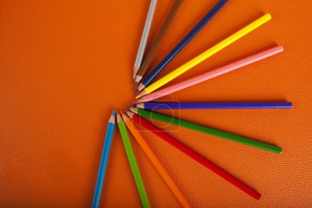 Foto de Crayones de colores dispuestos en una estrella, sobre un fondo naranja - Imagen libre de derechos