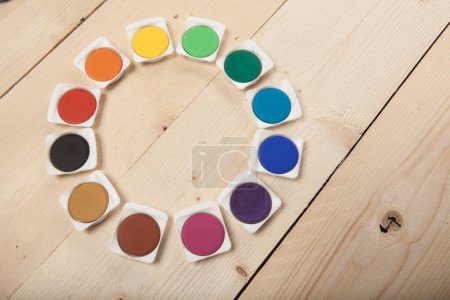 Téléchargez les photos : Cercle d'aquarelles colorées sur fond bois clair - en image libre de droit