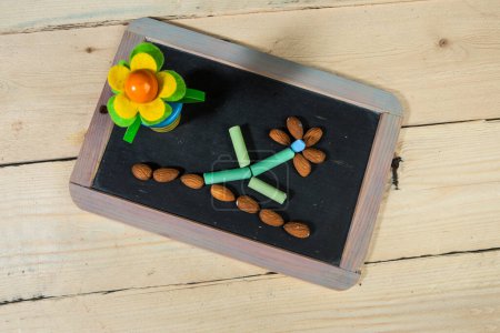 Photo for Blackboard with colored chalks that go to form a flower, isolated on a wooden table - Royalty Free Image
