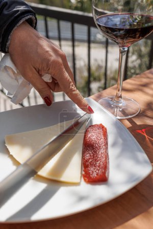 Téléchargez les photos : Une assiette avec une tranche de fromage et de la confiture maison à côté d'un verre de vin en plein air - en image libre de droit