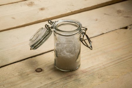 Foto de Recipiente de vidrio pequeño para sal gruesa en una mesa de madera - Imagen libre de derechos