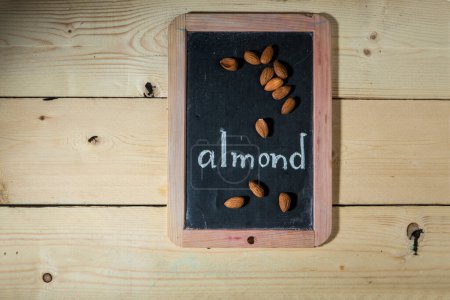 Photo for Black chalkboard on wooden background with the inscription: "almond" - Royalty Free Image