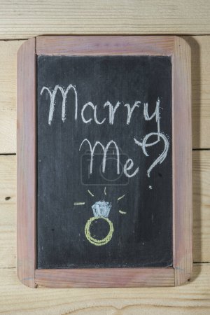 Photo for Black chalkboard on wooden background with the inscription: "Marry me?" - Royalty Free Image