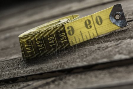Photo for Yellow dressmaker's tape measure over wooden boards - Royalty Free Image