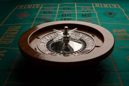 Téléchargez les photos : Roulette en bois isolée sur une table de jeu verte - en image libre de droit