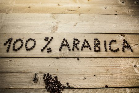 Téléchargez les photos : Écrit avec des grains de café "100 % arabica" sur une table en bois - en image libre de droit
