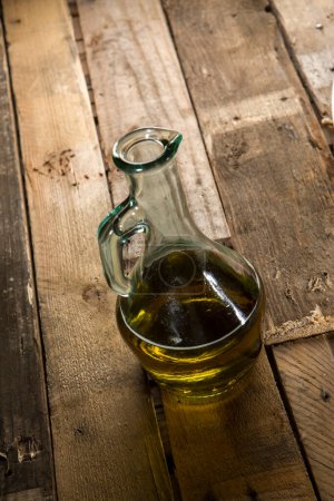 Foto de Cruet de vidrio con aceite dentro en una mesa de madera - Imagen libre de derechos