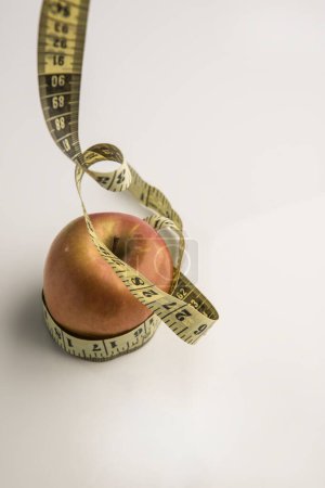 Téléchargez les photos : Une pomme avec mètre sur fond blanc - en image libre de droit