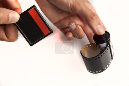 Foto de Película de 35 mm y tarjeta de memoria flash compacta, sostenida en la mano sobre fondo blanco. Presente y pasado - Imagen libre de derechos