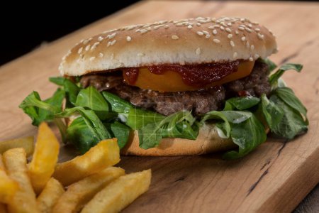 Téléchargez les photos : Sandwich avec hamburger tomate, salade et chips sur une table en bois - en image libre de droit