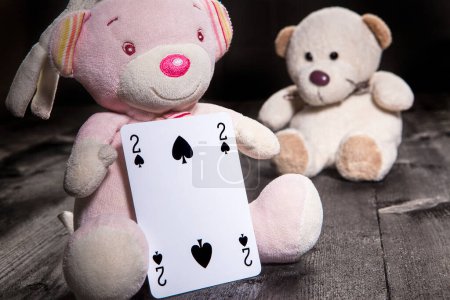 Photo for Little teddy bears over wooden background hold playing cards. Two of spades - Royalty Free Image