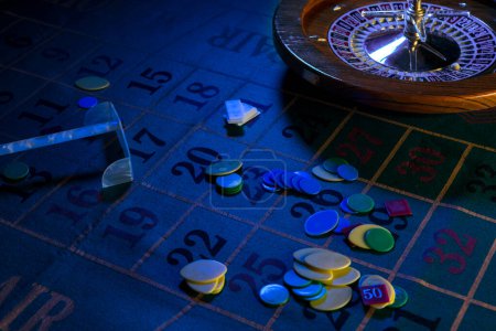 Photo for Wooden roulette wheel isolated over a green gaming table with colorful chips - Royalty Free Image