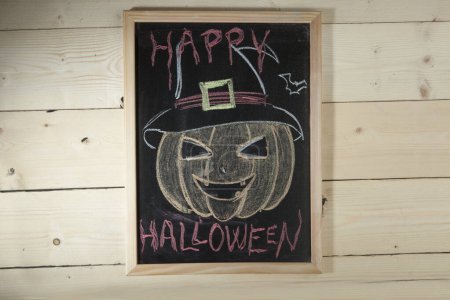 Photo for Black chalkboard on wooden background with the inscription: "Happy Halloween" - Royalty Free Image