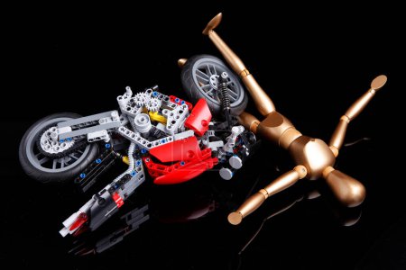 Photo for Cagliari, Italy - 12 January 2011: Wooden puppet has an accident with motorcycle made of lego, isolated on black background. - Royalty Free Image