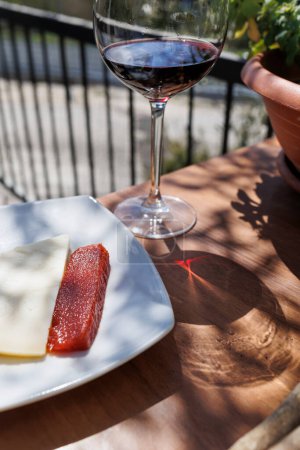 Photo for Plate with a slice of cheese and homemade jam next to a glass of wine in an outdoors setting - Royalty Free Image