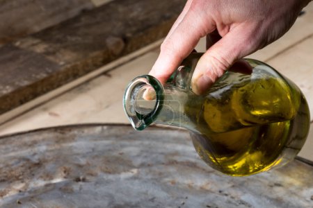Foto de Un hombre vierte aceite de un cruet en un plato - Imagen libre de derechos
