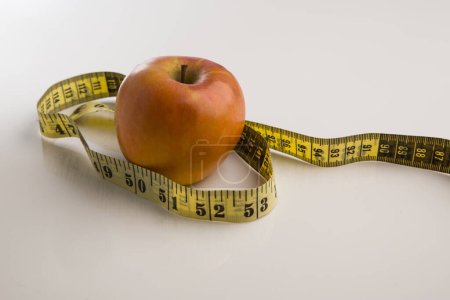 Photo for Apple and tape measure on white background - Royalty Free Image
