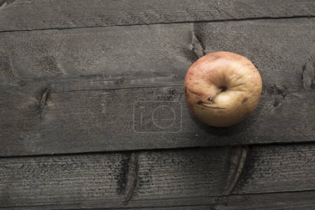 Téléchargez les photos : Pomme pourrie sur table en bois sombre - en image libre de droit