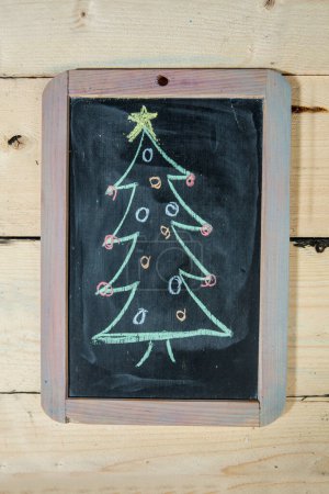 Photo for Blackboard with a Christmas tree drawn, isolated on a wooden table - Royalty Free Image