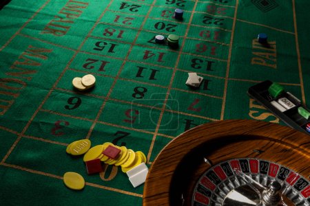Téléchargez les photos : Roue de roulette en bois isolée sur une table de jeu verte avec des puces colorées - en image libre de droit
