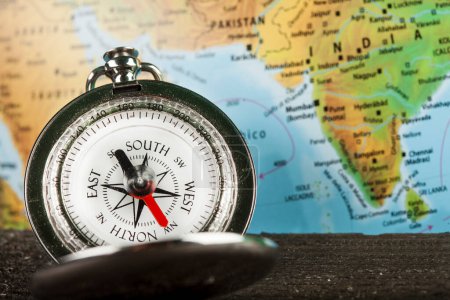 Photo for Compass in the foreground and the world map in the background - Royalty Free Image