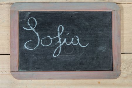 Téléchargez les photos : Tableau noir avec 'Sofia' mot sur bureau en bois. - en image libre de droit