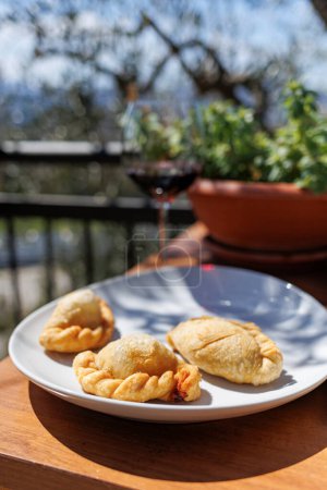 Photo for Detail presentation of fried ravioli on a white plate at an outdoor table with a glass of wine - Royalty Free Image