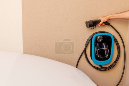 Téléchargez les photos : Homme tient le connecteur d'une borne de recharge de voiture électrique dans sa main - en image libre de droit