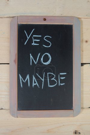 Photo for School blackboard on wooden table with "yes, no, maybe" written on it - Royalty Free Image