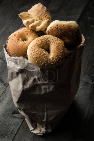 Foto de Varios tipos de pan característico y típico dentro de una bolsa de papel, aislado en una mesa de madera - Imagen libre de derechos