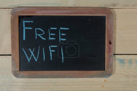 Foto de Pizarra con la inscripción 'wifi gratuito' sobre un fondo de madera - Imagen libre de derechos