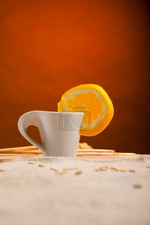 Foto de Taza de café con rebanada de naranja aislada sobre fondo rojo - Imagen libre de derechos