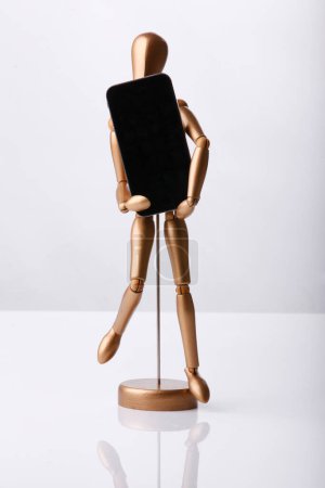 Téléchargez les photos : Cagliari, Italie - 12 janvier 2011 : Marionnette en bois tient un téléphone cellulaire à la main isolé sur fond blanc - en image libre de droit