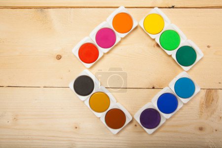 Foto de Acuarelas coloridas dispuestas en un cuadrado sobre una superficie de madera - Imagen libre de derechos