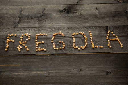 Foto de Letras "Fregola" con granos de pasta sueltos, aislados sobre una mesa de madera oscura - Imagen libre de derechos