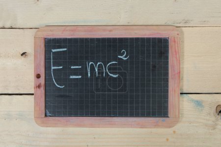 Photo for School blackboard on wooden table with "E mc two" written on it - Royalty Free Image