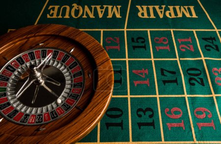 Photo for Roulette in legno isolata sopra un tavolo da gioco verde con fiches colorate - Royalty Free Image