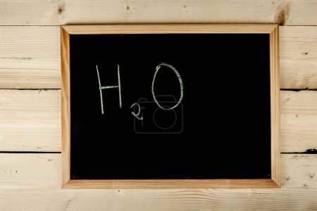 Photo for School blackboard on wooden table with "H2O" written on it - Royalty Free Image