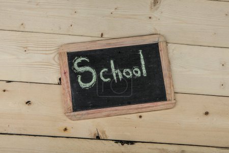 Photo for Black chalkboard on wooden background with the inscription: "School" - Royalty Free Image