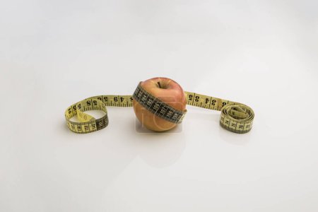 Téléchargez les photos : Pomme avec ruban à mesurer sur un grand fond blanc - en image libre de droit