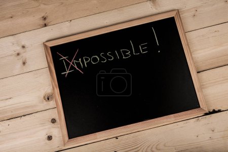 Téléchargez les photos : Tableau noir de l'école sur table en bois avec "Impossible" écrit dessus - en image libre de droit