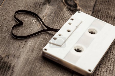 Téléchargez les photos : Cassette audio avec ruban en forme de coeur, isolée sur une table en bois - en image libre de droit