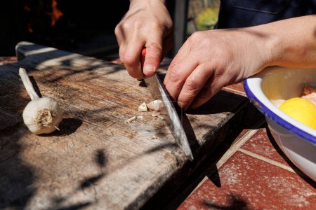 Foto de El detalle de las manos que cortan el diente del ajo con el cuchillo a la tabla que corta - Imagen libre de derechos