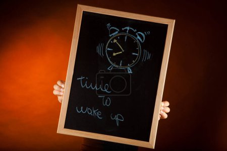 Photo for "time is wake up" and a hand indicating the stop sign, isolated on orange background - Royalty Free Image