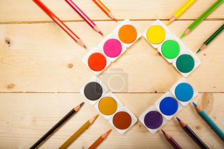Foto de Acuarelas y lápices de colores en la superficie de madera - Imagen libre de derechos