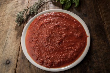 Foto de Salsa de tomate dentro del plato blanco en la mesa de madera y otros ingredientes varios - Imagen libre de derechos