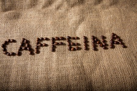 Téléchargez les photos : Écrit "caféine" avec des grains de café sur un sac de jute - en image libre de droit