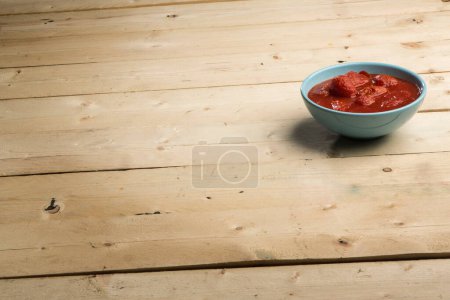 Photo for Bowl with tomato puree over a wooden table - Royalty Free Image