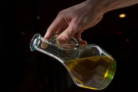 Foto de Mano verter aceite de un frasco de vidrio - Imagen libre de derechos